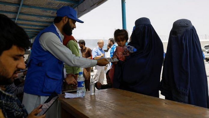 A displaced Afghan woman receives cash aid from a WSTA employee at a cash aid distribution centre for displaced people in Kabul | File Photo: Reuters