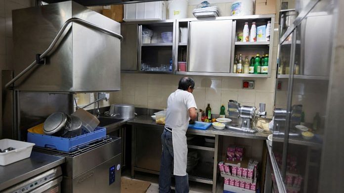A migrant worker cleans dishes at a restaurant prior to lunch time, in Milan, Italy | Reuters/Claudia Greco