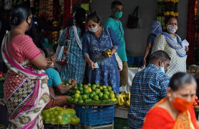 A woman wearing a protective face mask buys fruit in a market, amidst the spread of Covid-19 in Mumbai | File Photo: Reuters