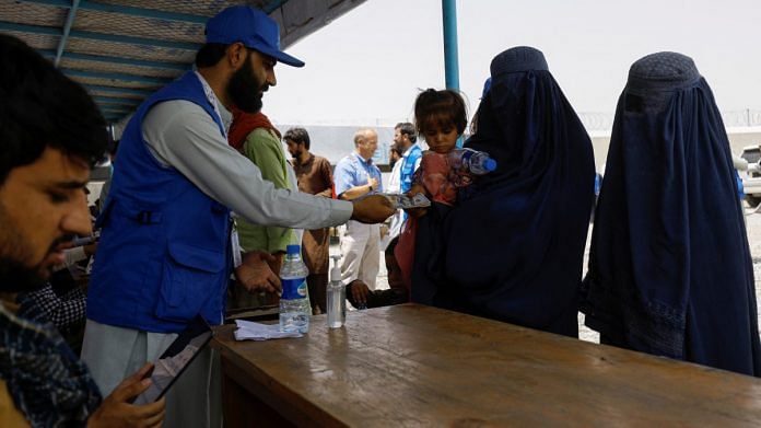A displaced Afghan woman receives cash aid from a WSTA employee at a cash aid distribution centre for displaced people in Kabul, Afghanistan | Reuters