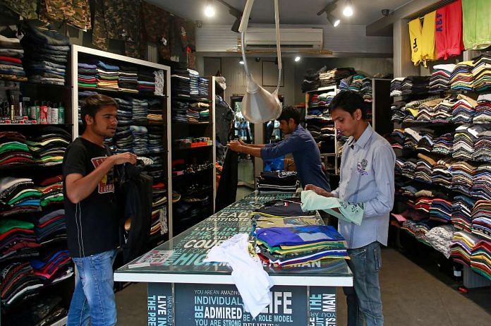Salesmen fold shirts inside a clothes store at a market in Mumbai | Reuters