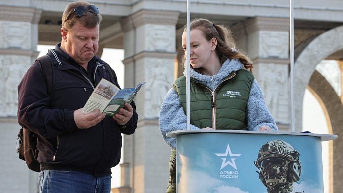 A man studies a leaflet given by a campaign member promoting Russian army service in Moscow, Russia on 12 April 2023 | Photo: REUTERS