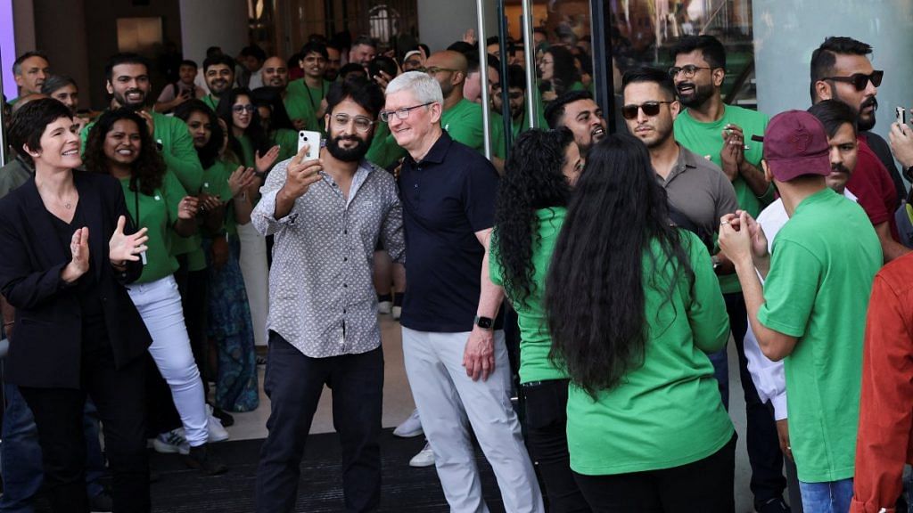 A man takes a picture with Apple CEO Tim Cook during the inauguration of India's first Apple retail store in Mumbai, on 18 April 2023 | Reuters