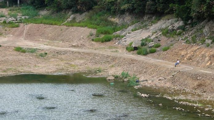 A man draws water with a pump on a dried-up reservoir in Changxing, Zhejiang province, China | Reuters/Aly Song