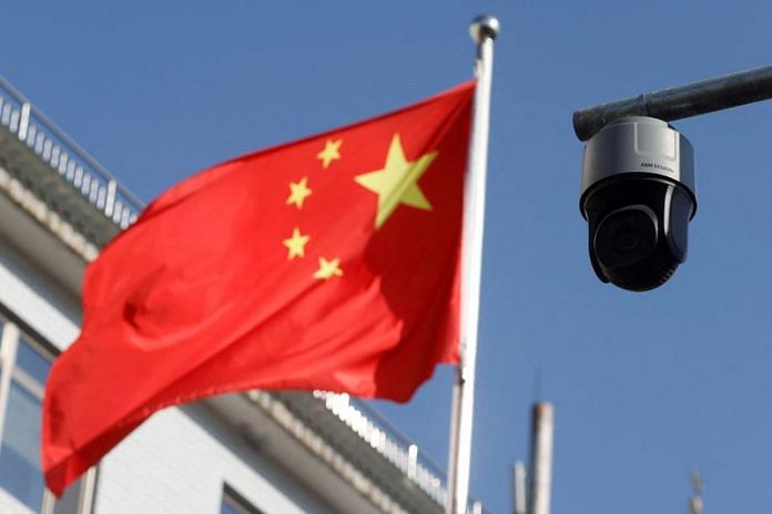 A security surveillance camera overlooking a street is pictured next to a nearby fluttering flag of China in Beijing | Reuters/Carlos Garcia Rawlins