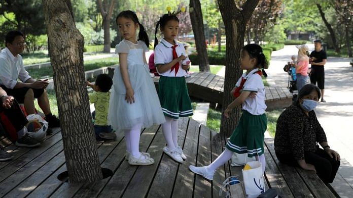 Children play next to adults at a park in Beijing | File Photo: Reuters