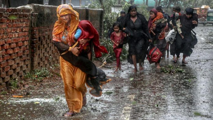 People move from their homes to take shelter in the nearest cyclone shelter at Shah Porir Dwip during the landfall of cyclone Mocha in Teknaf, Bangladesh, on 14 May 2023 | Reuters