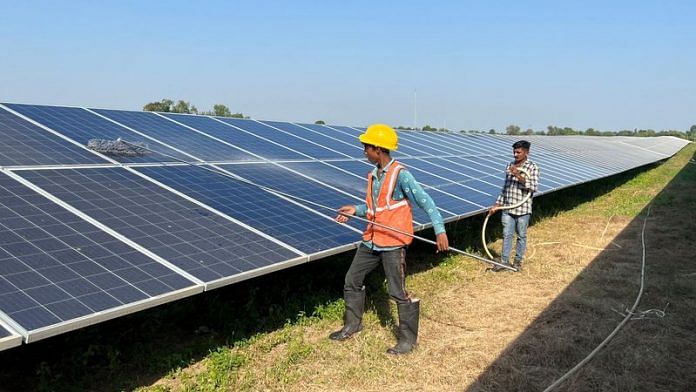 Workers clean panels at a solar park in Modhera, India's first round-the-clock solar-powered village, in Gujarat | File Photo: Reuters