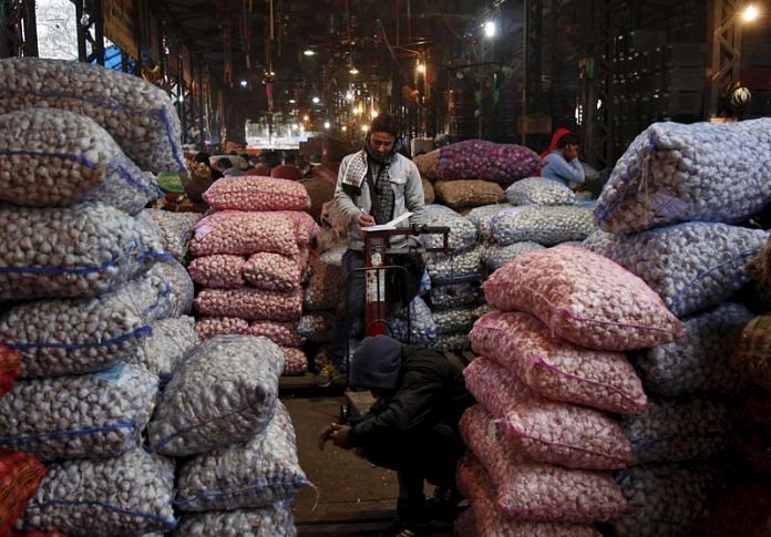 An accountant works next to the stacked sacks of garlic at a wholesale vegetable market in Chandigarh | Reuters file photo