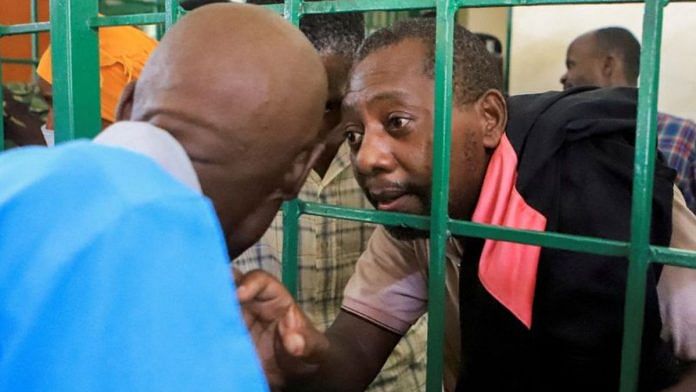 Paul Mackenzie, 50, talks to a man from a steel-grilled dock at the Shanzu Law Courts, in Mombasa, Kenya | Reuters file photo