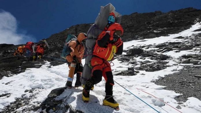 Ngima Tashi Sherpa walks as he carries a Malaysian climber while rescuing him from the death zone above camp four at Everest, on 13 May 2023 | Gelje Sherpa/Handout via Reuters