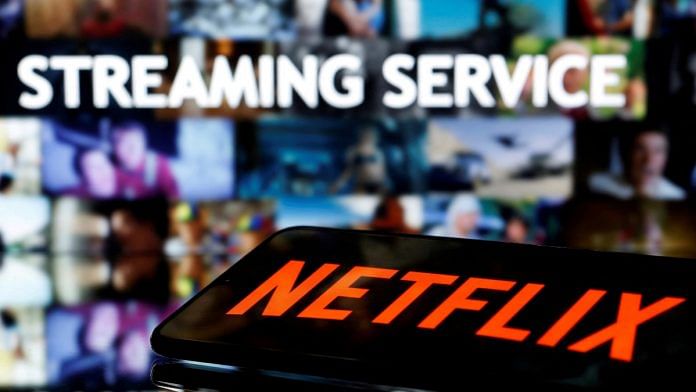 A smartphone with the Netflix logo lies in front of displayed 'Streaming service' words | Illustration by Dado Ruvic/Reuters