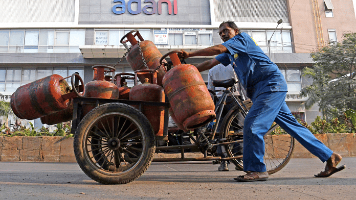 File photo of a man pushing his cart near a building with Adani logo in Mumbai | ANI