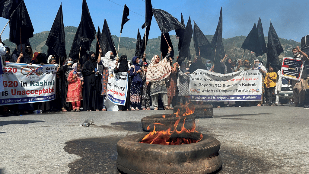 People carry black flags and set tyres ablaze to condemn India's decision to host the G20 Tourism Working Group meeting in Srinagar, during a protest in Muzaffarabad, Pakistan-administrated Kashmir, May 22, 2023. REUTERS/Stringer