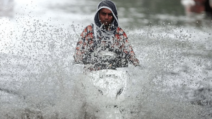A person rides a scooter through a waterlogged road during monsoon rain showers in Mumbai |