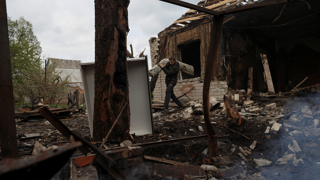 A neighbour carries items from a house destroyed by a Russian drone strike in the village of Malotaranivka in Donetsk region, Ukraine | Reuters/Sofiia Gatilova