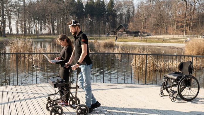 A scientist accompanies the volunteer walking with the help of the BSI system | Credit CHUV | Gilles Weber