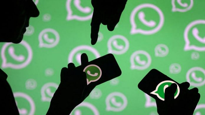 Men pose with smartphones in front of displayed Whatsapp logo in this illustration | Reuters