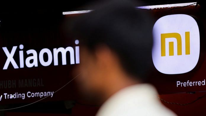 A man walks past a logo of Xiaomi, a Chinese manufacturer of consumer electronics, outside a shop in Mumbai | Reuters