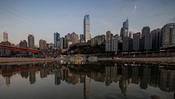 The city skyline is reflected in a pool left on the dry riverbed of the receding Jialing river, a tributary of the Yangtze, that is approaching record-low water levels during a regional drought in Chongqing, China | Reuters