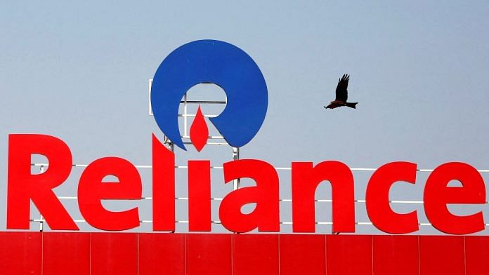 A bird flies past a Reliance Industries logo installed on its mart in Ahmedabad, India | Reuters