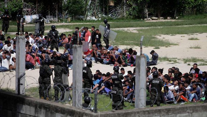 Members of the Military Police of Public Order stand guard as inmates sit in the yard at Tamara prison after the Honduras Armed Forces took over the control of the prisons nationwide as part of the 