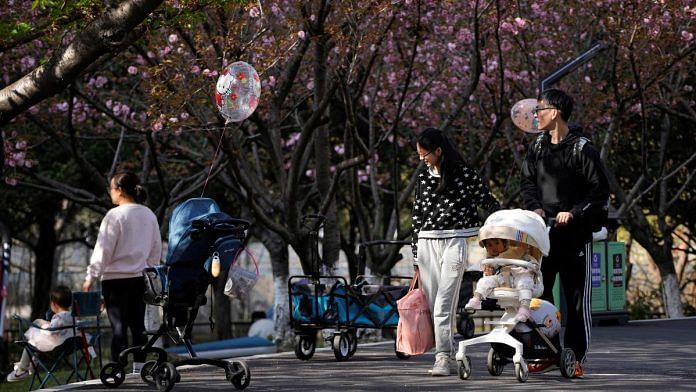 A parents pushes a stroller with a baby in a park in Shanghai, China | Reuters