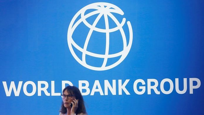 A participant stands near a logo of World Bank at the International Monetary Fund - World Bank Annual Meeting 2018 in Nusa Dua, Bali, Indonesia | Reuters