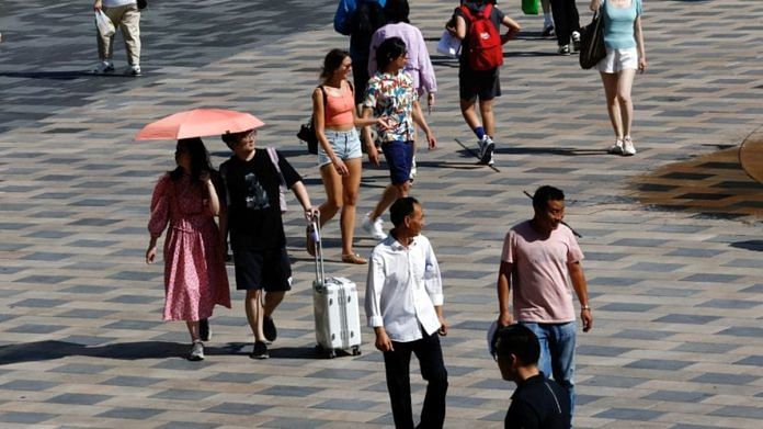 People walk at a shopping area amid an orange alert for heatwave in Beijing | Reuters