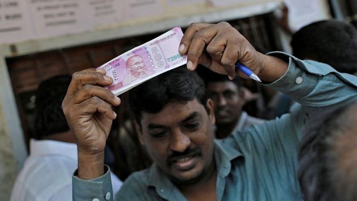 man holds 2000 Indian rupees notes as he gets out of a bank in Mumbai, on 24 November, 2016/Reuters