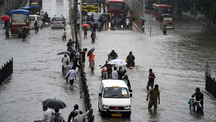 People wade through a waterlogged road after heavy rains in Mumbai | File Photo: Reuters