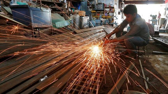 A worker grinds a metal gate inside a household furniture manufacturing factory in Ahmedabad/Reuters