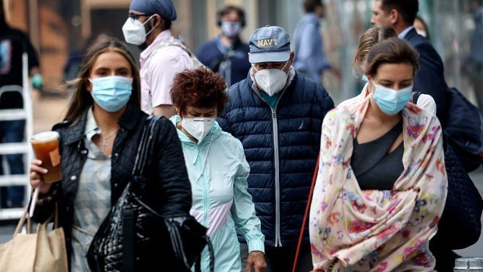 People wear protective face masks as they walk in midtown Manhattan as haze and smoke caused by wildfires in Canada continue to linger over New York City, on 9 June 2023 | Reuters/Mike Segar