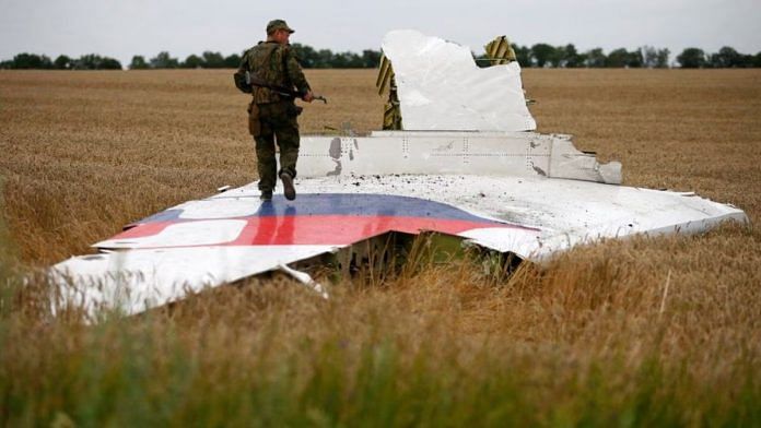 An armed pro-Russian separatist stands on wreckage of the Malaysia Airlines Boeing 777 | REUTERS/Maxim Zmeyev