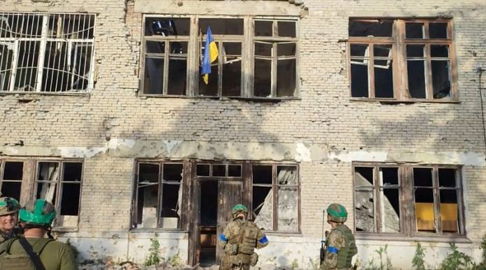 Ukrainian soldiers stand in front of a building with a Ukrainian flag on it, during an operation that claims to liberate the first village amid a counter-offensive, in a location given as Blahodatne, Donetsk Region, Ukraine, in this screengrab taken from a handout video released on 11 June, 2023/Reuters