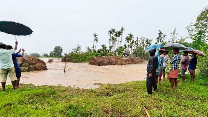 People stand on a damaged embankment washed out by the floods due to incessant rainfall at Gohaigaon near Kampur in Nagaon District of Assam | ANI Photo