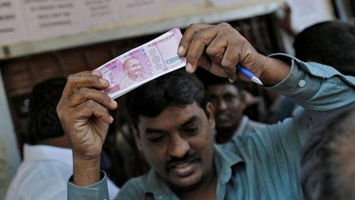 A man holds 2000 Indian rupees notes as he gets out of a bank in Mumbai | Reuters