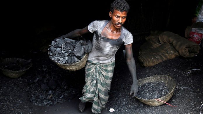 A worker carries coal in a basket in an industrial area in Mumbai | Reuters/Shailesh Andrade