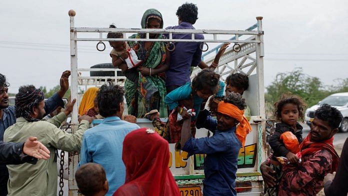 A man carries a child from a truck during an evacuation before the arrival of cyclone Biparjoy in Jakhau in the western state of Gujarat, June 14, 2023 | Reuters/Francis Mascarenhas