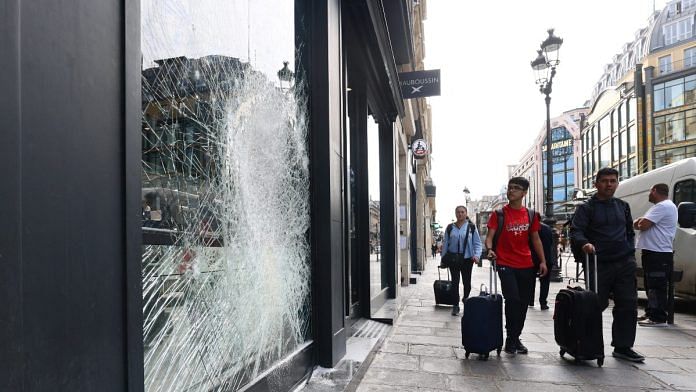 People walk past the damaged window of a store vandalised during clashes between protesters and police following the death of Nahel, a 17-year-old killed by a French police officer | Reuters/Yves Herman