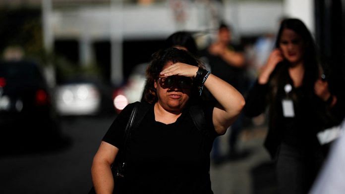 A woman walks along the sidewalk, shielding herself from the sun with her hand as high temperatures continue, in Monterrey, Mexico June 28, 2023 | Reuters/Daniel Becerril