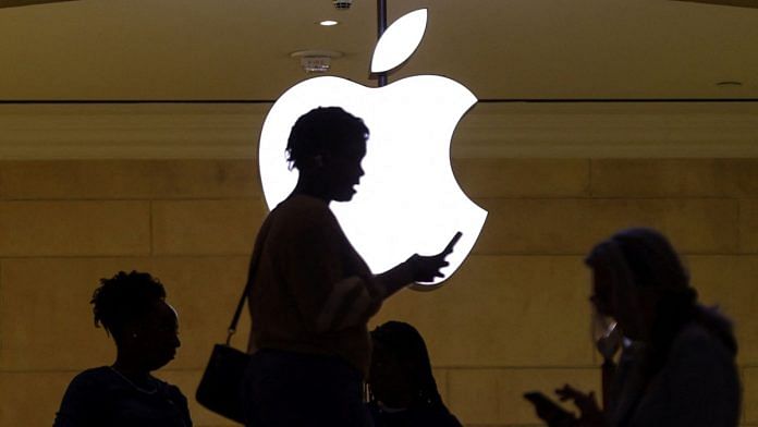 Representational image of a woman using her phone with Apple logo in the background | Reuters