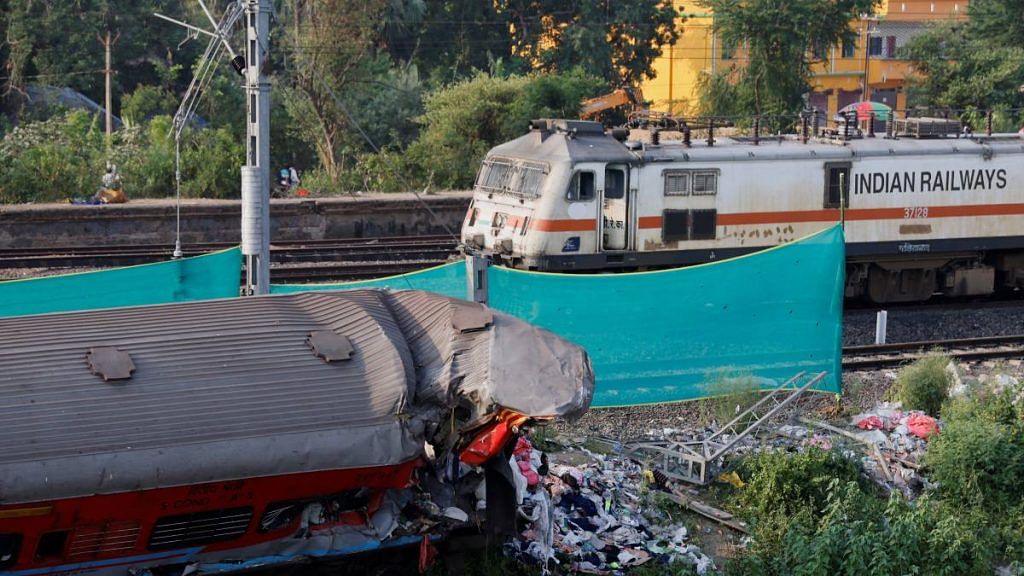 A train moves past a damaged coach, after the tracks were restored, at the site of a train collision following the accident in Balasore, on 5 June 2023 | Reuters