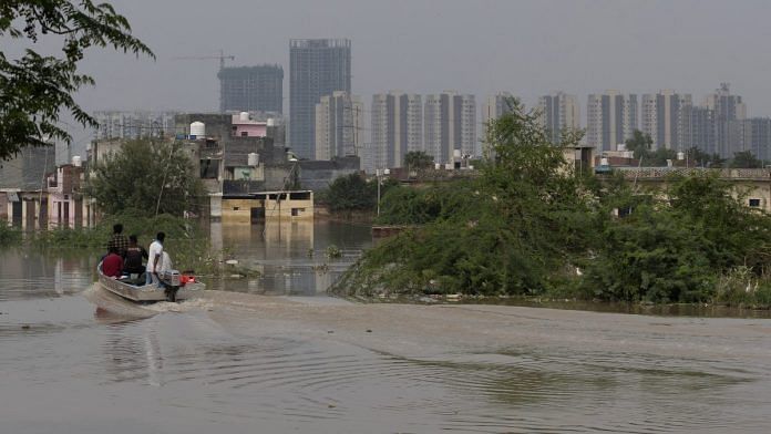 People ride a boat to look for strandad residents at a flooded colony, after a rise in waters of the river Yamuna due to heavy monsoon rain, in New Delhi | Reuters