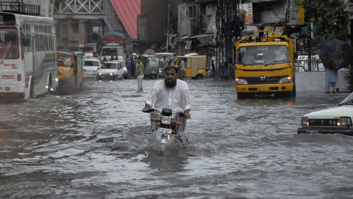 A man rides on a motorcycle amid flood waters along a road during the monsoon season in Rawalpindi, Pakistan | Reuters