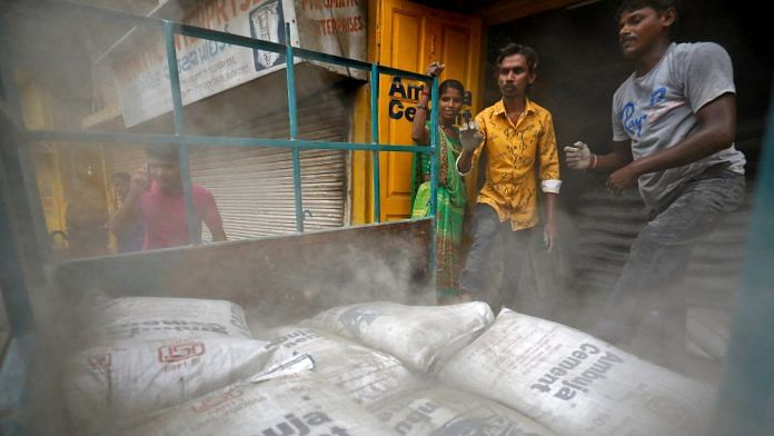 Workers load Ambuja cement bags into a load carrier to be carried to a construction site in Ahmedabad, India | Reuters