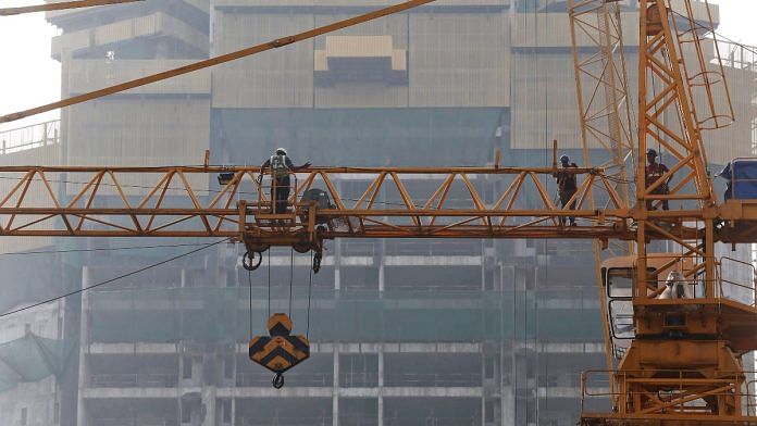 Construction workers are pictured on a crane at a construction site in Mumbai, India | Reuters