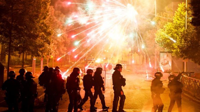 French police stand in position as fireworks go off during clashes following the death of Nahel, a 17-year-old teenager killed by a French police officer during a traffic stop, in Nanterre, Paris suburb, France | Reuters