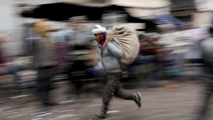 A labourer runs across a wholesale market in the old quarters of Delhi/File Photo: Reuters
