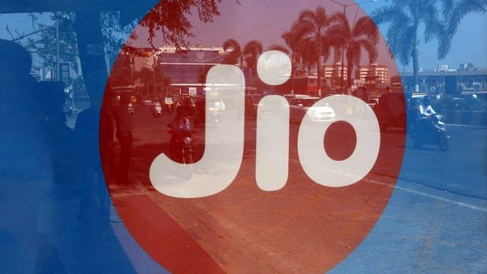 Commuters are reflected on an advertisement of Reliance Industries' Jio telecoms unit, at a bus stop in Mumbai | File Photo: Reuters